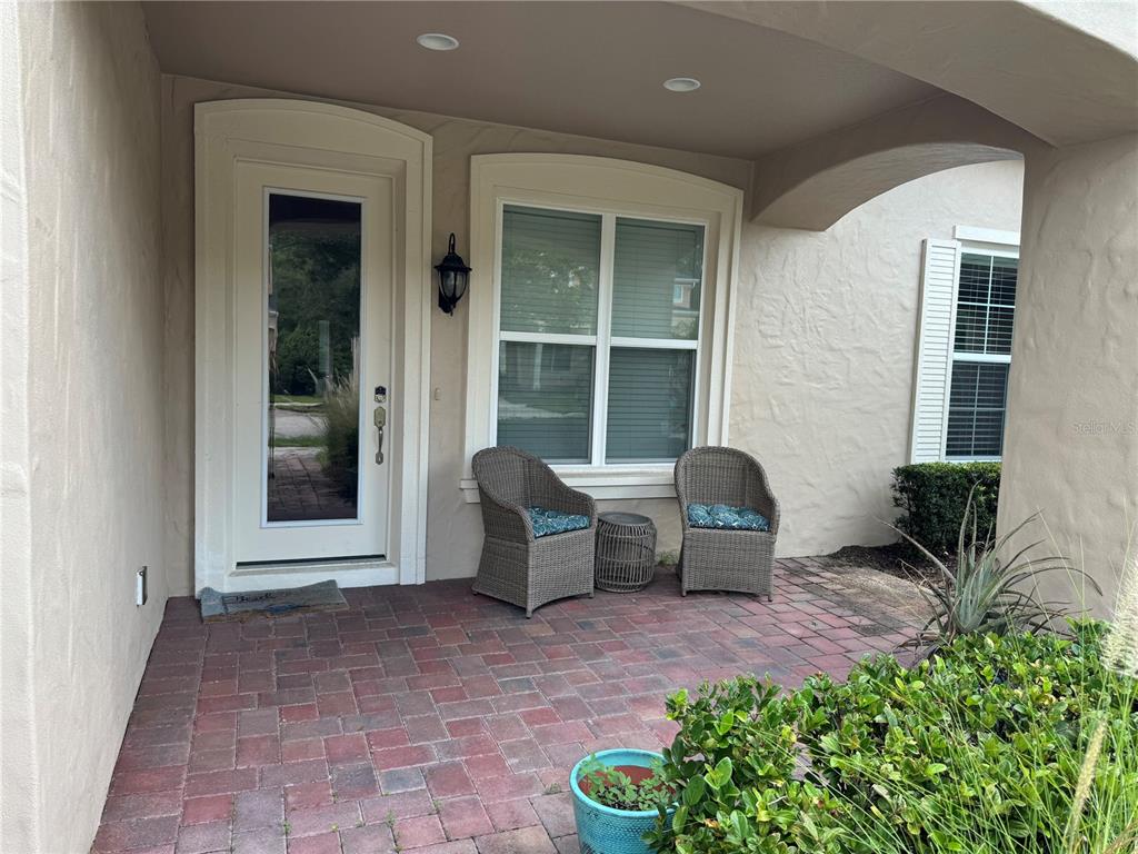 A paved front porch features two wicker chairs, a small table, and a glass-paneled door — 3422 TORRE BOULEVARD, NEW SMYRNA BEACH, FL