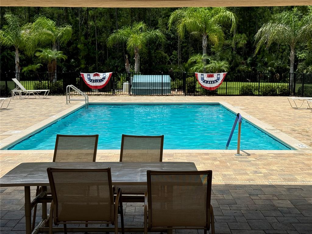 A rectangular swimming pool is surrounded by a paved patio with outdoor dining furniture — 3422 TORRE BOULEVARD, NEW SMYRNA BEACH, FL