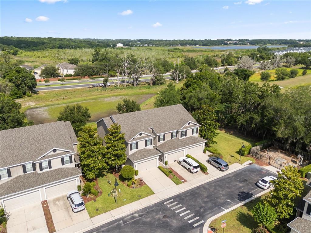 An aerial view shows two multi-story suburban townhomes with garages and driveways near a road — 1512 GROUNDSEL LANE, OCOEE, FL