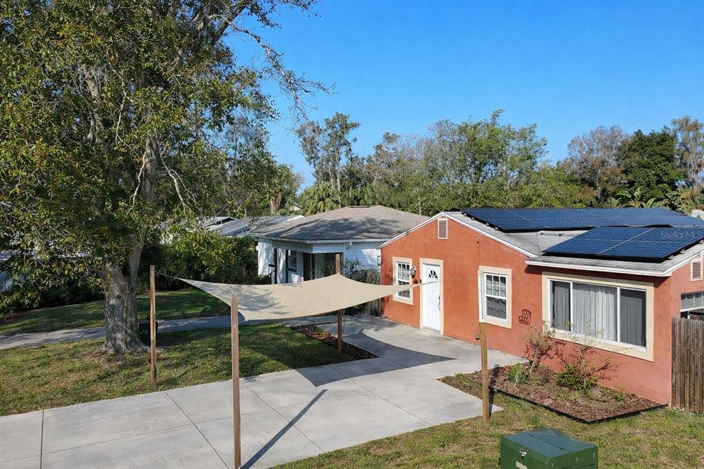 An exterior view of a terracotta-colored house with solar panels and a shade sail canopy — 5613 19TH AVENUE S, GULFPORT, FL