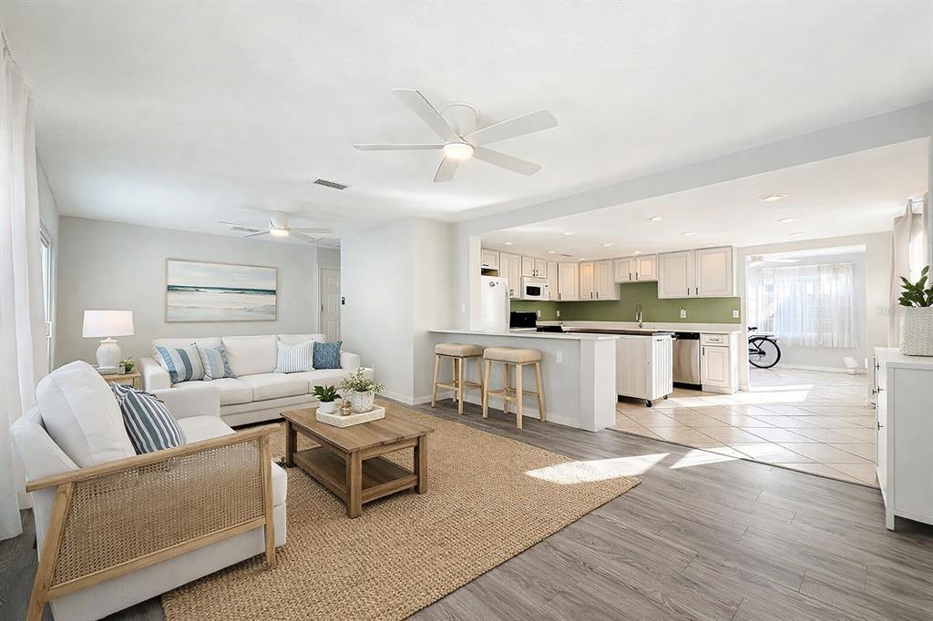 An open-concept living room with light wood floors connects to a kitchen with green walls — 5613 19TH AVENUE S, GULFPORT, FL