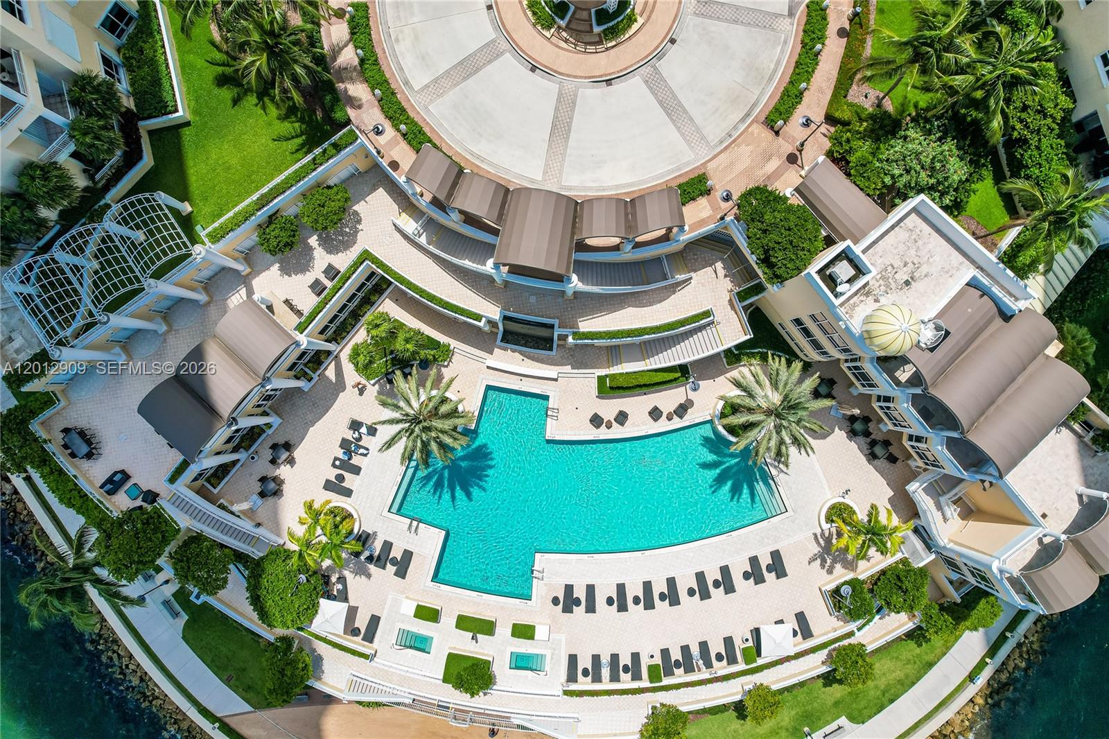 An aerial view shows a large swimming pool surrounded by a patio, landscaping, and buildings — 848 Brickell Key Dr # 1903, Miami FL 33131, MIAMI, FL