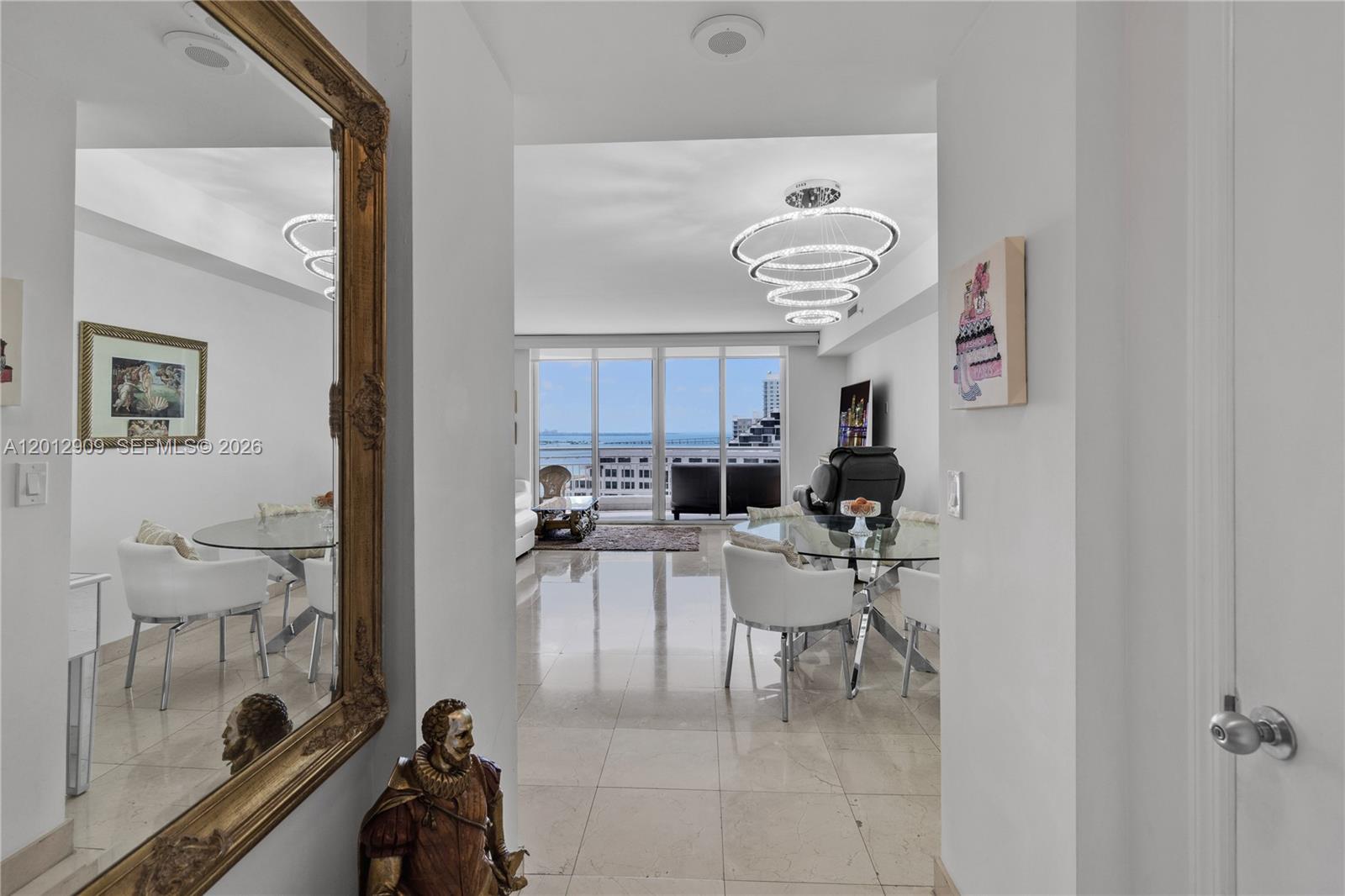 A bright living and dining area features marble floors, a modern chandelier, and balcony views — 848 Brickell Key Dr # 1903, Miami FL 33131, MIAMI, FL