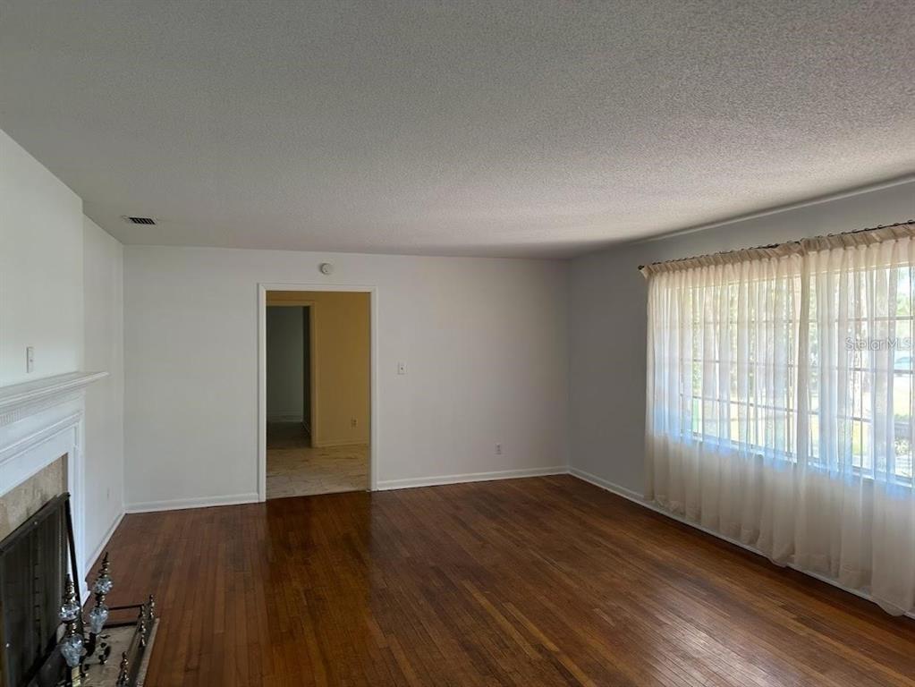A living room with hardwood floors, a fireplace, and a large window with sheer curtains — 1333 SE 17TH STREET, OCALA, FL