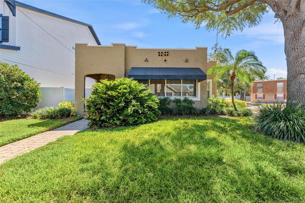 A tan stucco house with a flat roof, dark awning, and a front lawn — 1618 S ARRAWANA AVENUE, TAMPA, FL
