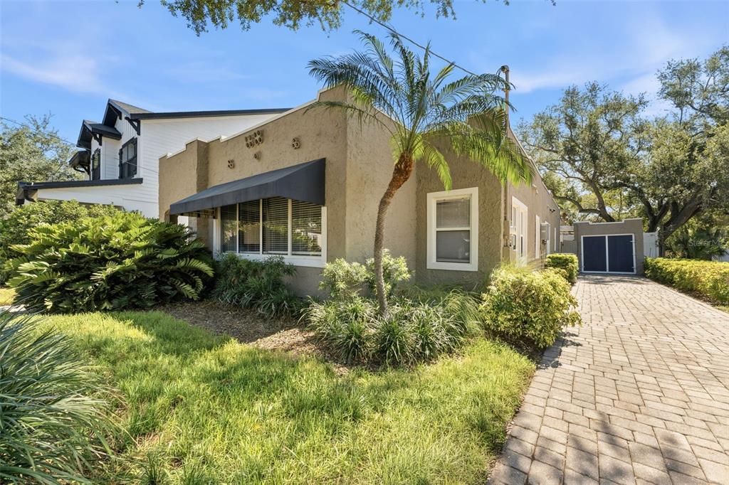 A tan stucco house with a black awning and a paved driveway under a palm tree — 1618 S ARRAWANA AVENUE, TAMPA, FL