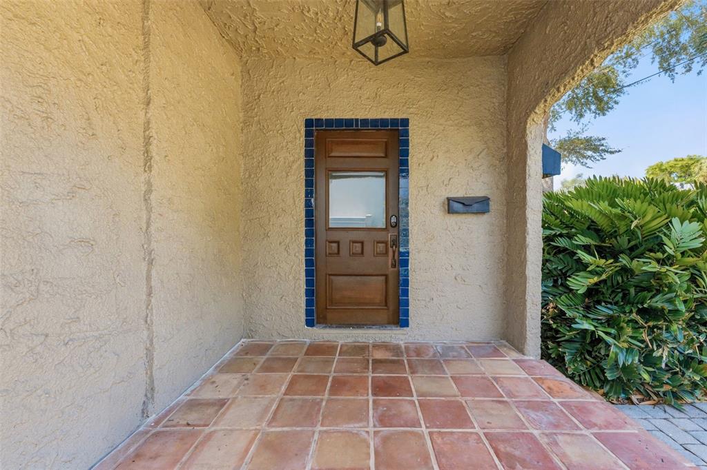 A covered entryway features a wooden door with blue tile trim and terracotta floor tiles — 1618 S ARRAWANA AVENUE, TAMPA, FL