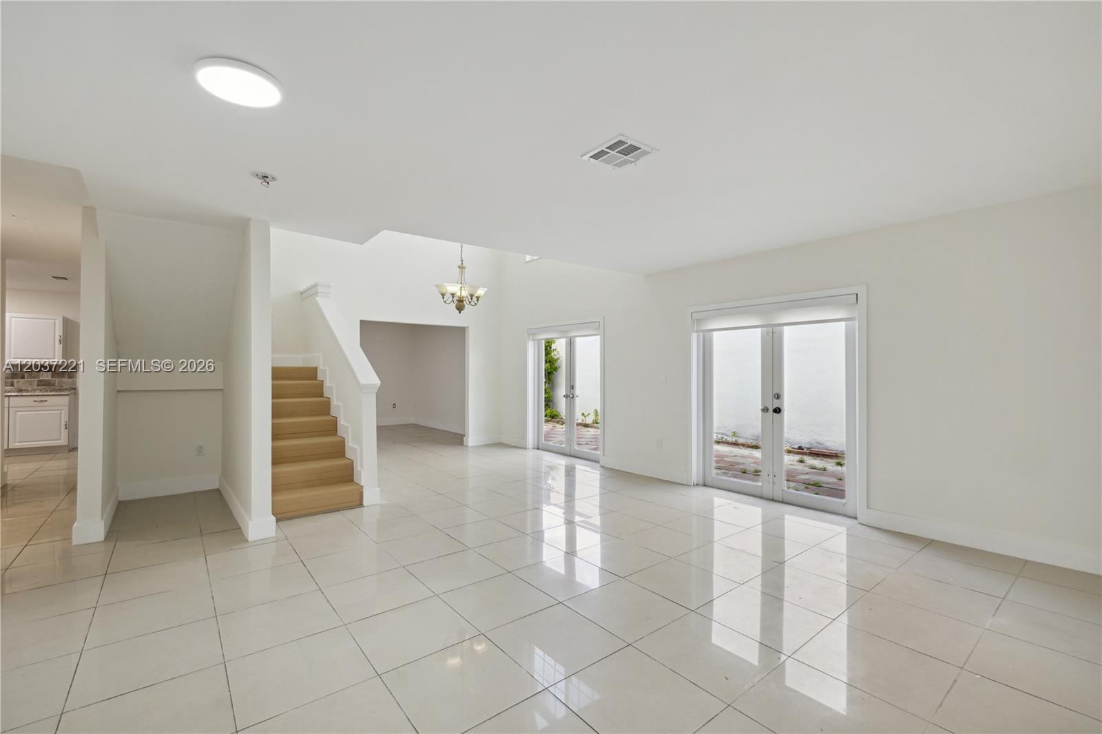 A bright, open living area features white tile floors, a staircase, and glass patio doors — 15131 SW 58th St, Miami FL 33193, MIAMI, FL