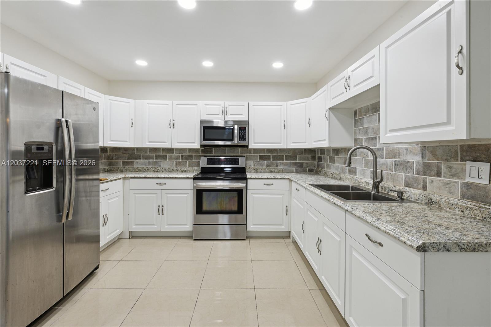 A kitchen features white cabinets, granite countertops, stainless steel appliances, and a tiled backsplash — 15131 SW 58th St, Miami FL 33193, MIAMI, FL