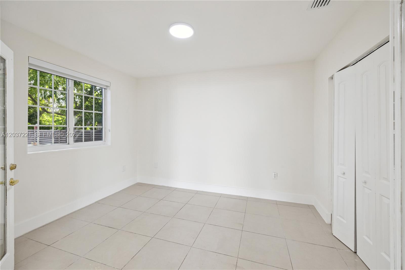 An empty room features white walls, light-colored tile flooring, a window, and a closet — 15131 SW 58th St, Miami FL 33193, MIAMI, FL