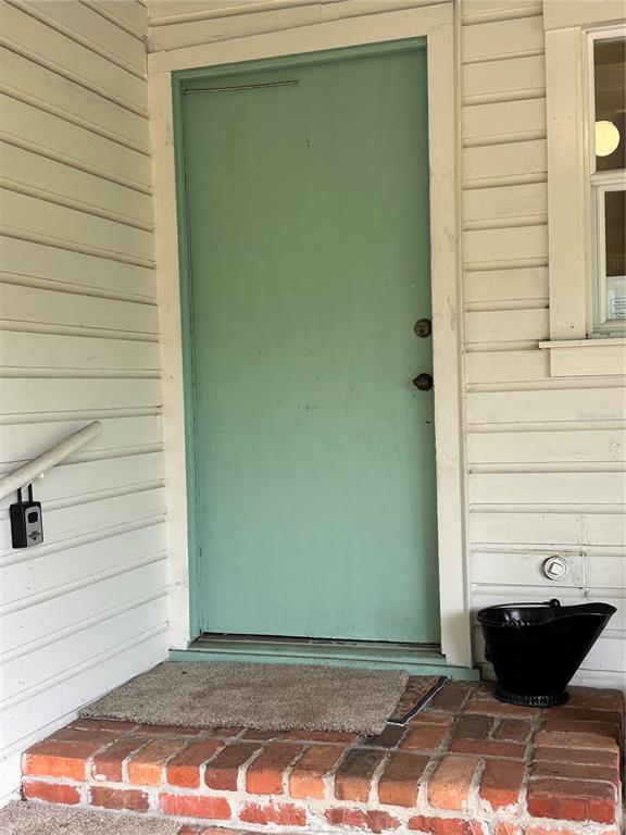 A green door with a black lockbox sits above a brick step and doormat — 3900 CHALET SUZANNE DRIVE, LAKE WALES, FL
