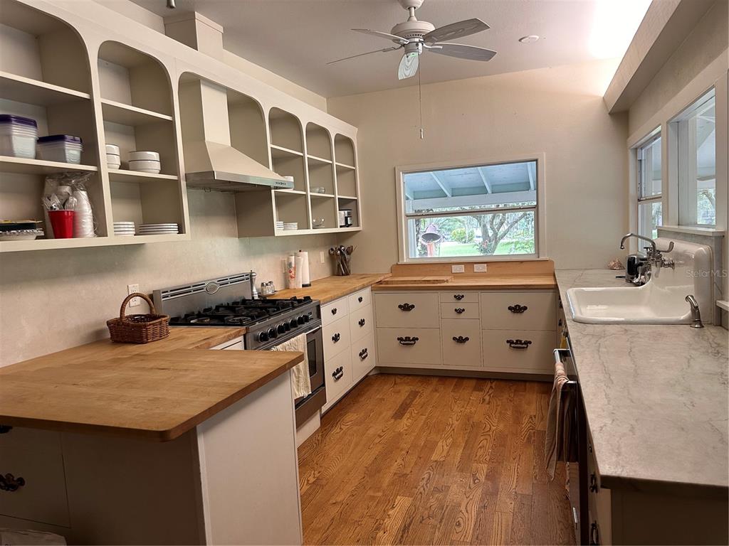 A kitchen features white cabinetry, open shelving, wood countertops, a gas range, and a sink — 3900 CHALET SUZANNE DRIVE, LAKE WALES, FL