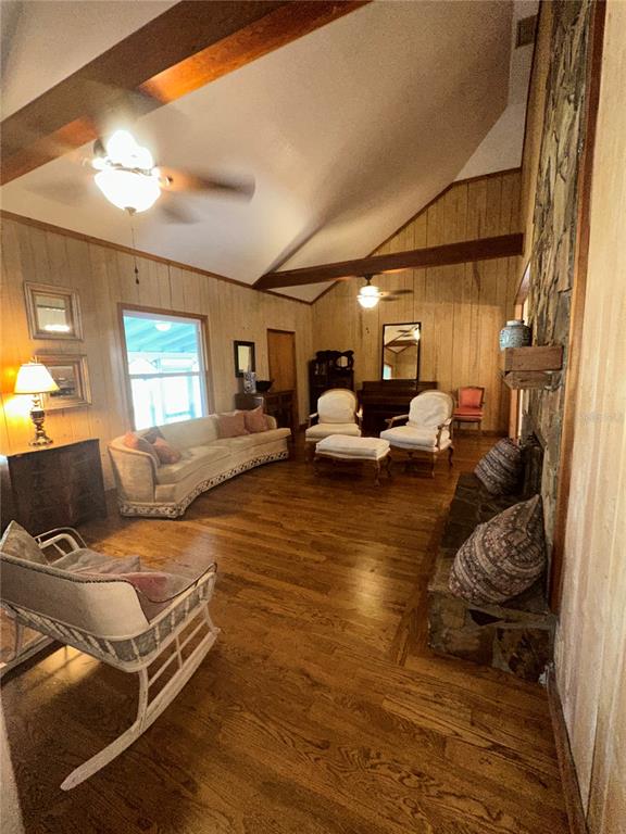 A living room features wood-paneled walls, exposed ceiling beams, hardwood floors, and a stone fireplace — 3900 CHALET SUZANNE DRIVE, LAKE WALES, FL