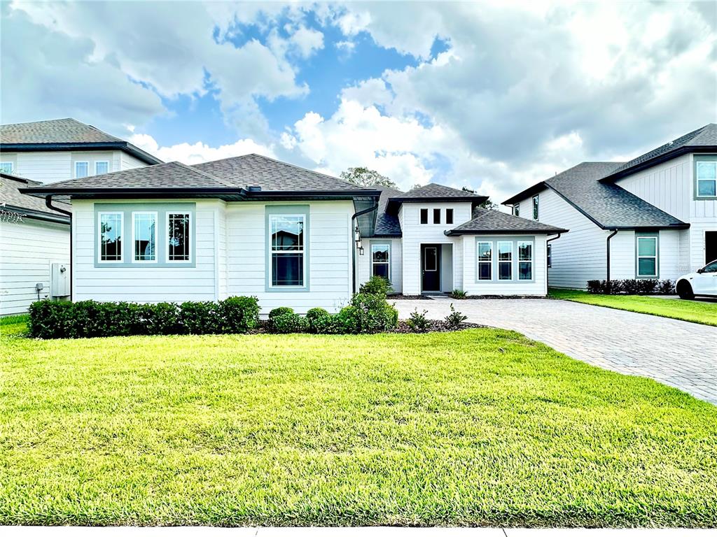 A white single-story house with a gray roof and a paved driveway under a cloudy sky — 17552 LAKE STAR ROAD, WINTER GARDEN, FL
