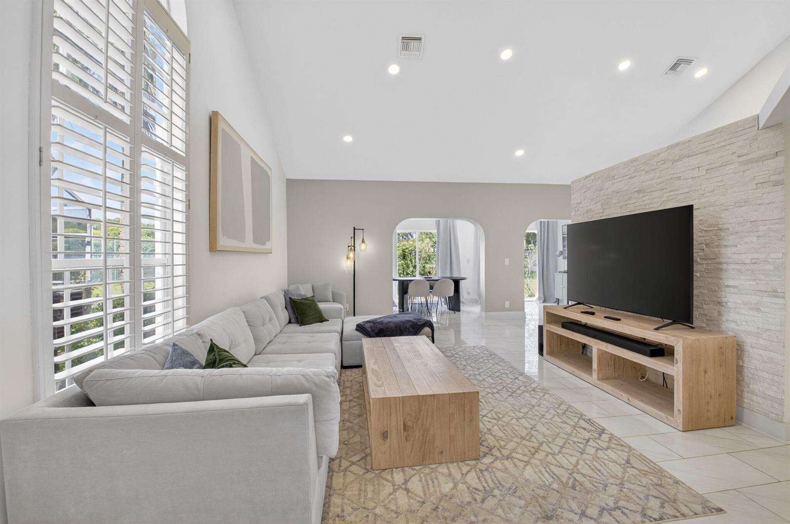 A living room features a light gray sectional sofa, wood coffee table, and stone-accented wall — 5111 Sabal Gardens Lane # 4, Boca Raton FL 33487, BOCA RATON, FL