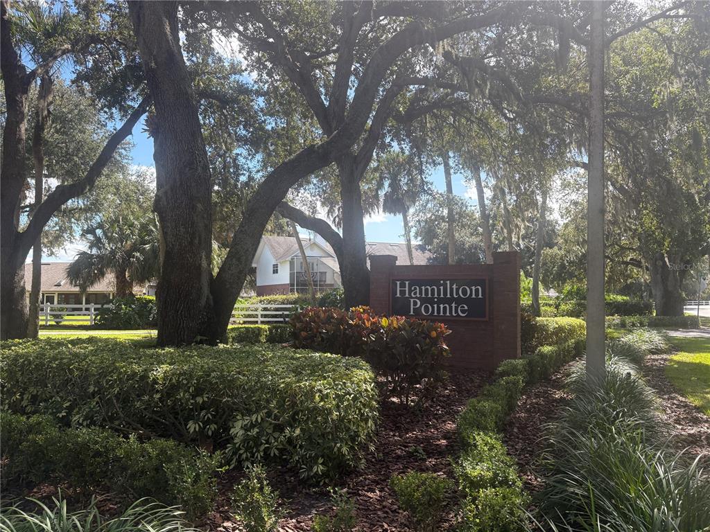 A brick sign for Hamilton Pointe stands in a landscaped area with large oak trees — 725 HERITAGE DRIVE NE, WINTER HAVEN, FL