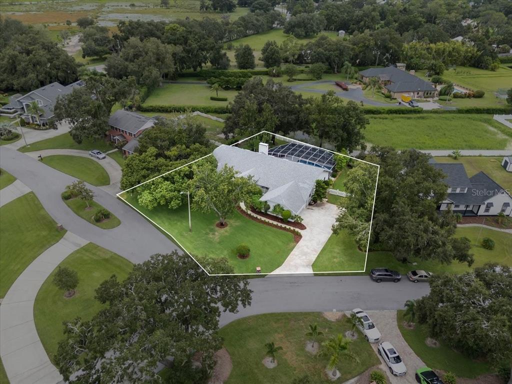 An aerial view shows a single-story house with a screened pool and a large yard — 725 HERITAGE DRIVE NE, WINTER HAVEN, FL