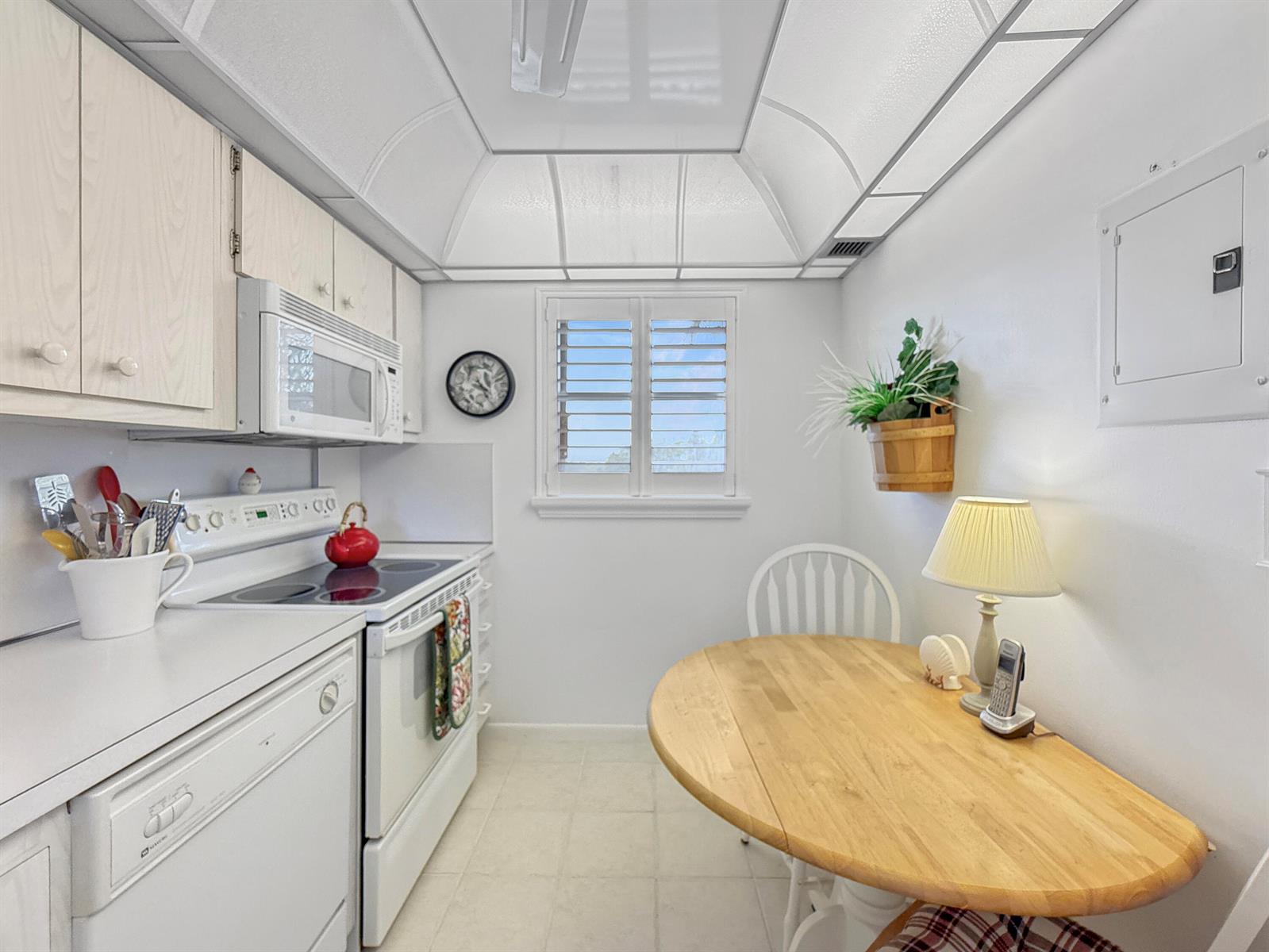 A white kitchen features a wooden dining table, a window, and a tray ceiling — 555 NW 4th Avenue # 401, Boca Raton FL 33432, BOCA RATON, FL