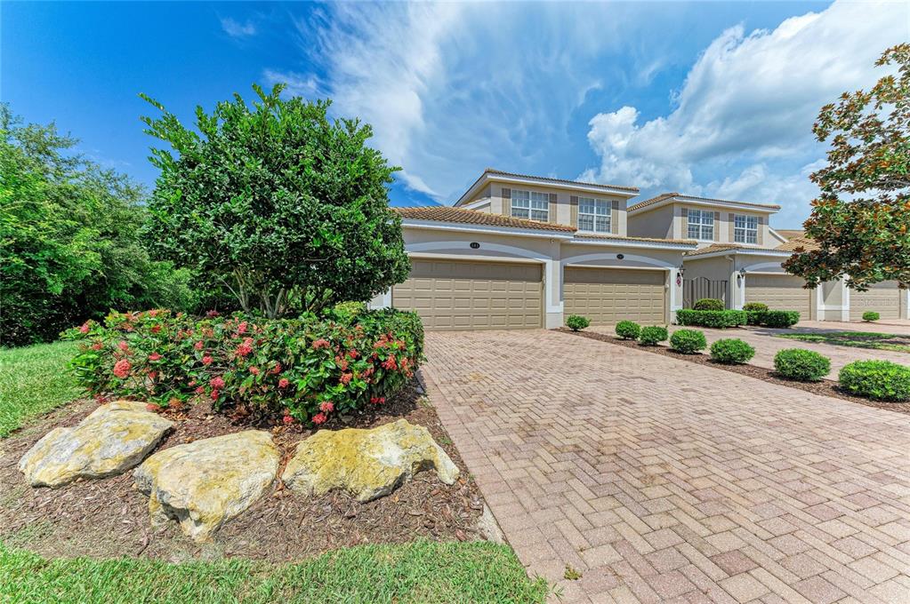 A two-story house with a paved driveway and two attached garage doors — 419 WINDING BROOK LANE UNIT 101, BRADENTON, FL
