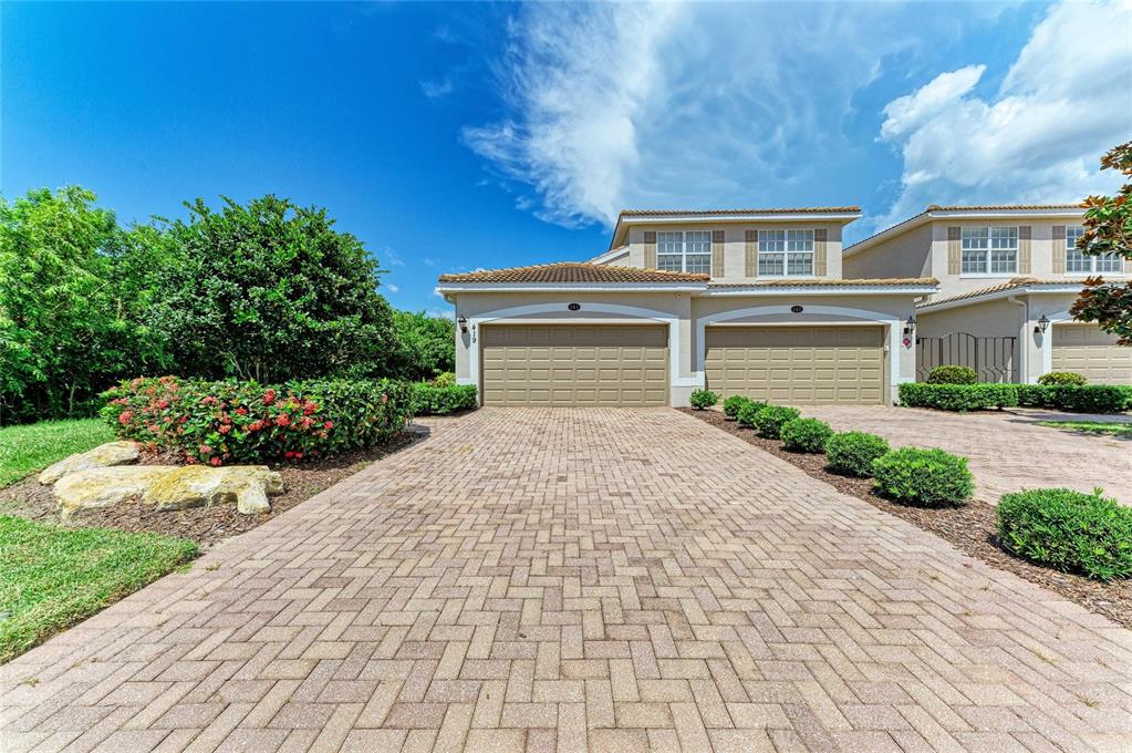 A two-story residential building with two garage doors and a paved driveway — 419 WINDING BROOK LANE UNIT 101, BRADENTON, FL