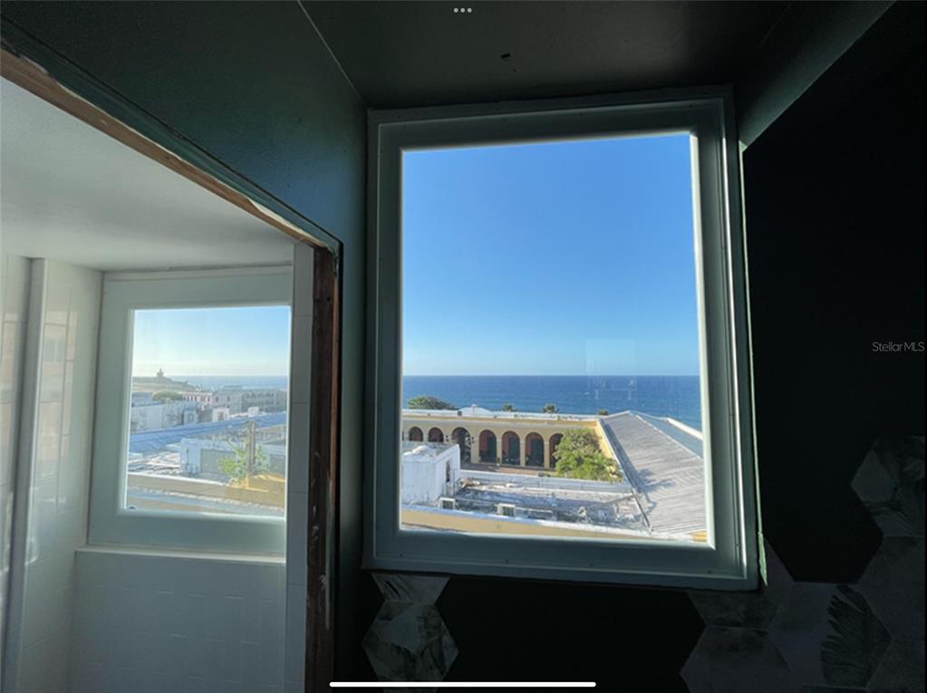 A view of the ocean and nearby buildings through two windows in an unfinished room — 9 DEL MERCADO UNIT 4, SAN JUAN, PR
