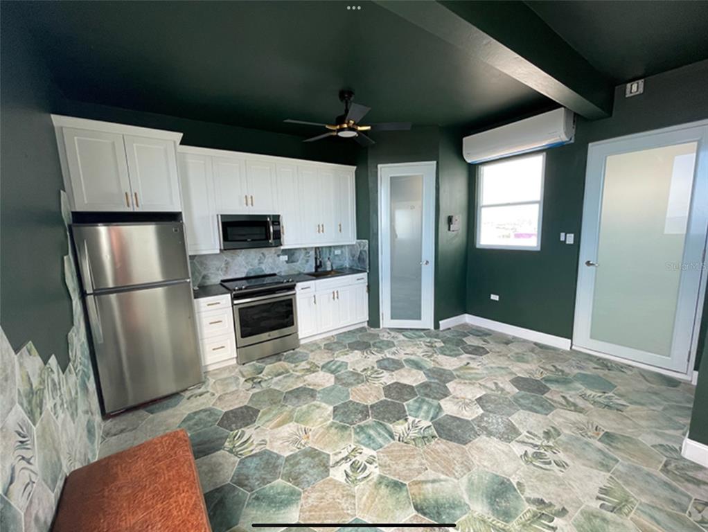 A kitchen features dark green walls, white cabinets, stainless steel appliances, and patterned hexagonal floor tiles — 9 DEL MERCADO UNIT 4, SAN JUAN, PR