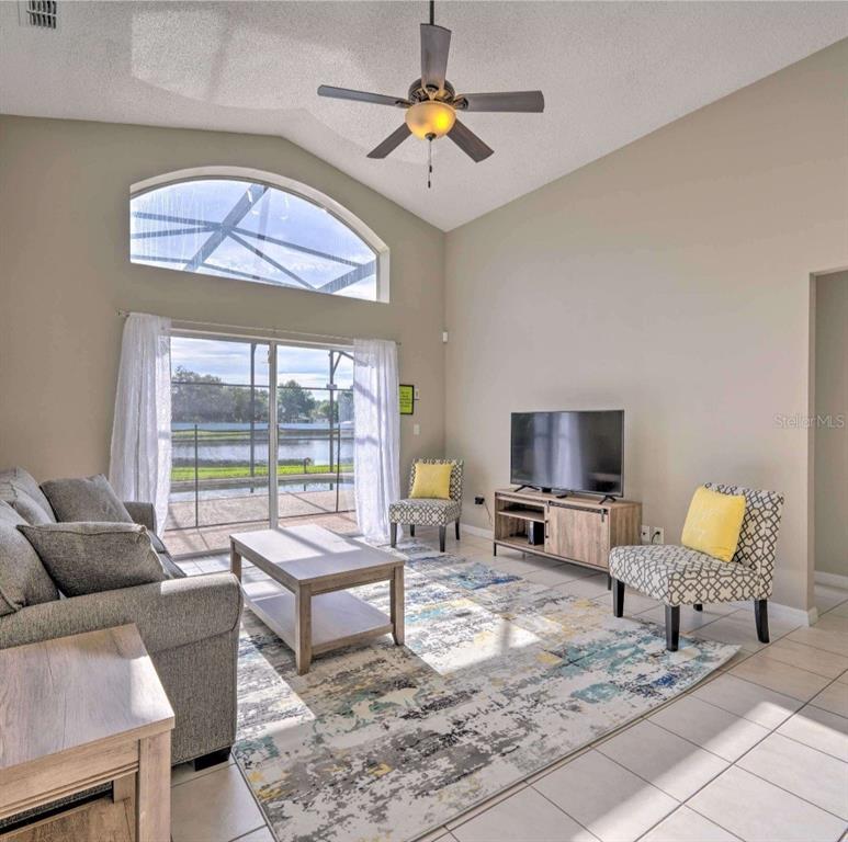 A living room features a vaulted ceiling, a ceiling fan, and a large arched window — 1310 SEASONS BOULEVARD, KISSIMMEE, FL