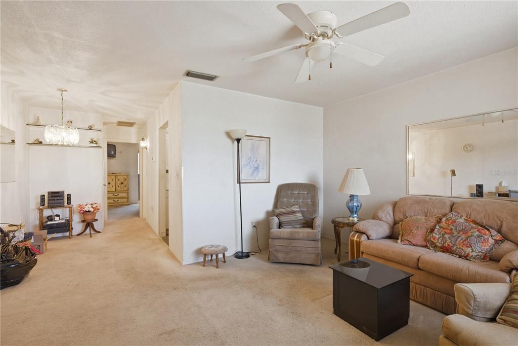 A living room with beige carpet, a ceiling fan, a sofa, and a recliner — 8126 112TH STREET UNIT 306, SEMINOLE, FL