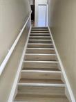 A straight staircase with wood-look treads and white trim leads to an upper landing — 14905 Pleasant Bay Lane # 6204, Naples FL 34119, NAPLES, FL