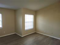 An empty room with beige walls, wood-look flooring, and two windows with white blinds — 14905 Pleasant Bay Lane # 6204, Naples FL 34119, NAPLES, FL