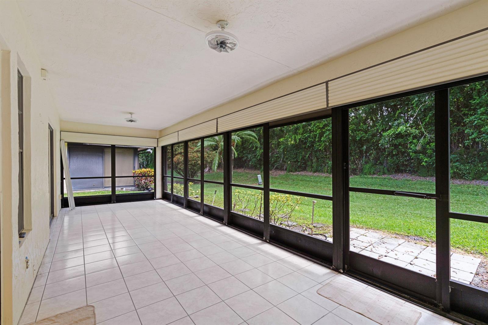 A tiled sunroom features screened walls, ceiling fans, and a view of a grassy backyard — 10044 Andrea Lane # A, Boynton Beach FL 33437, BOYNTON BEACH, FL