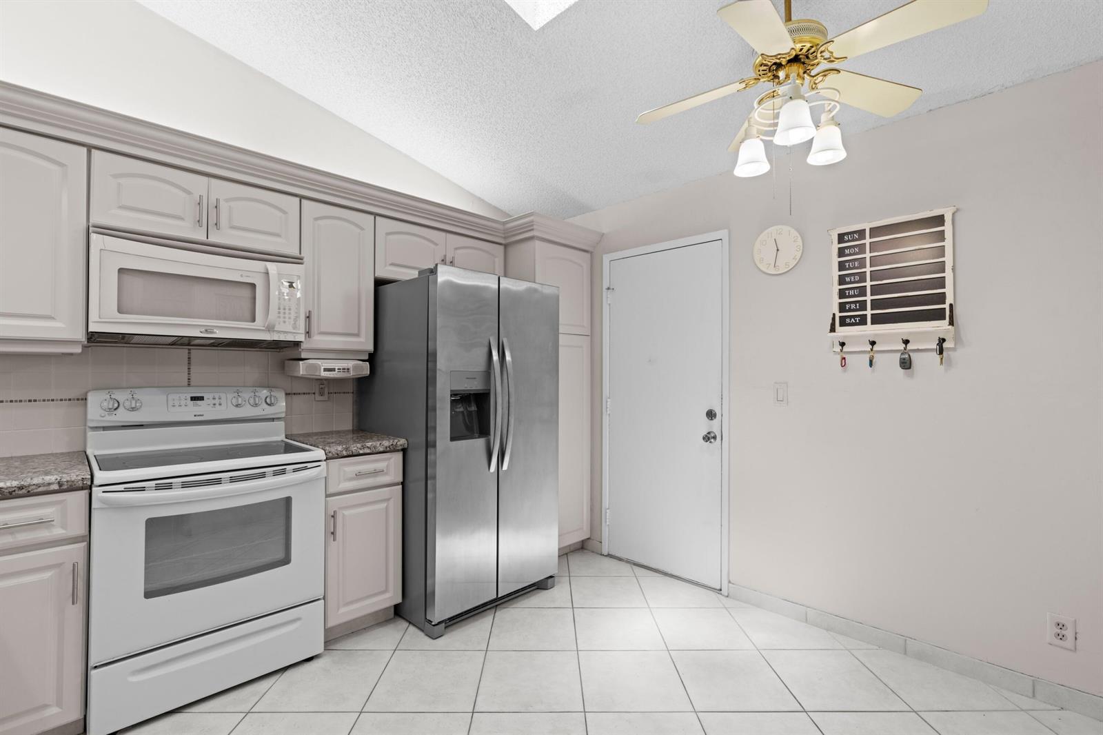 A kitchen features light-colored cabinetry, stainless steel appliances, a white stove, and tile flooring — 10044 Andrea Lane # A, Boynton Beach FL 33437, BOYNTON BEACH, FL