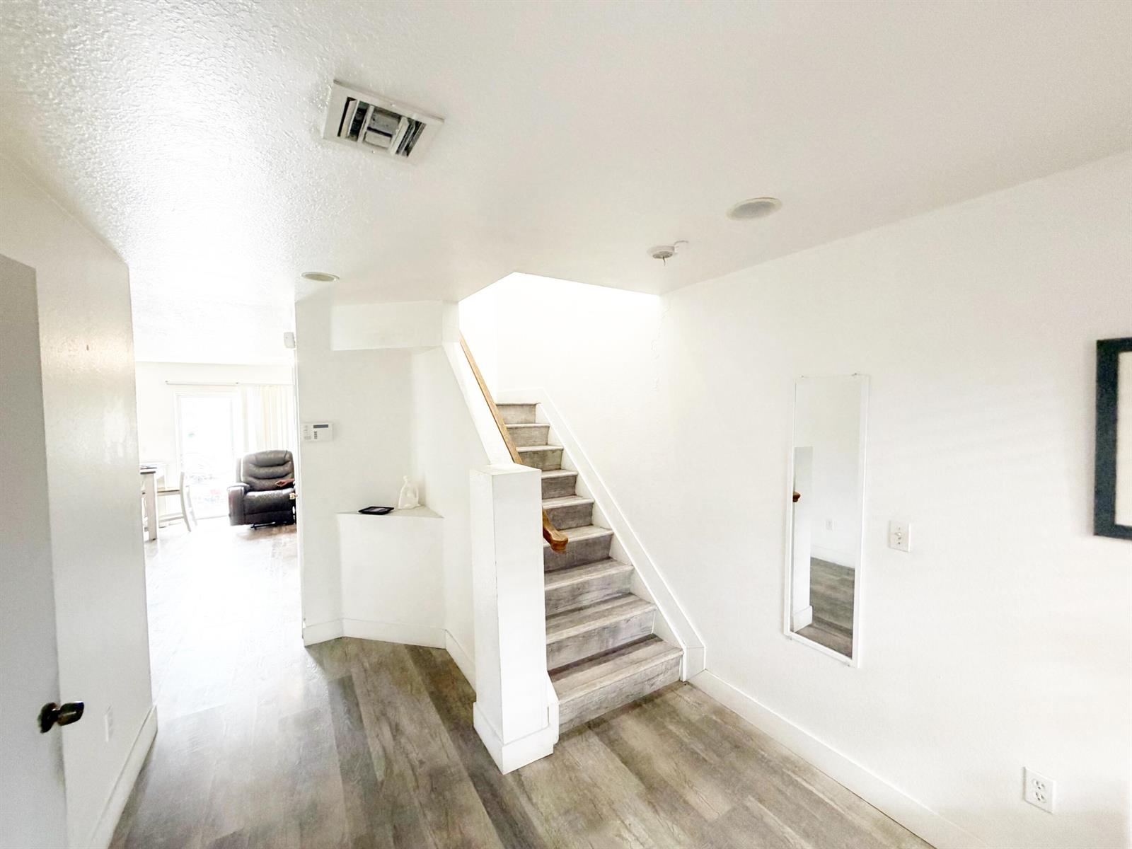 An entryway features wood-look flooring, a staircase with a wooden handrail, and a wall mirror — 2769 NW 13th Street # 6, Pompano Beach FL 33069, POMPANO BEACH, FL