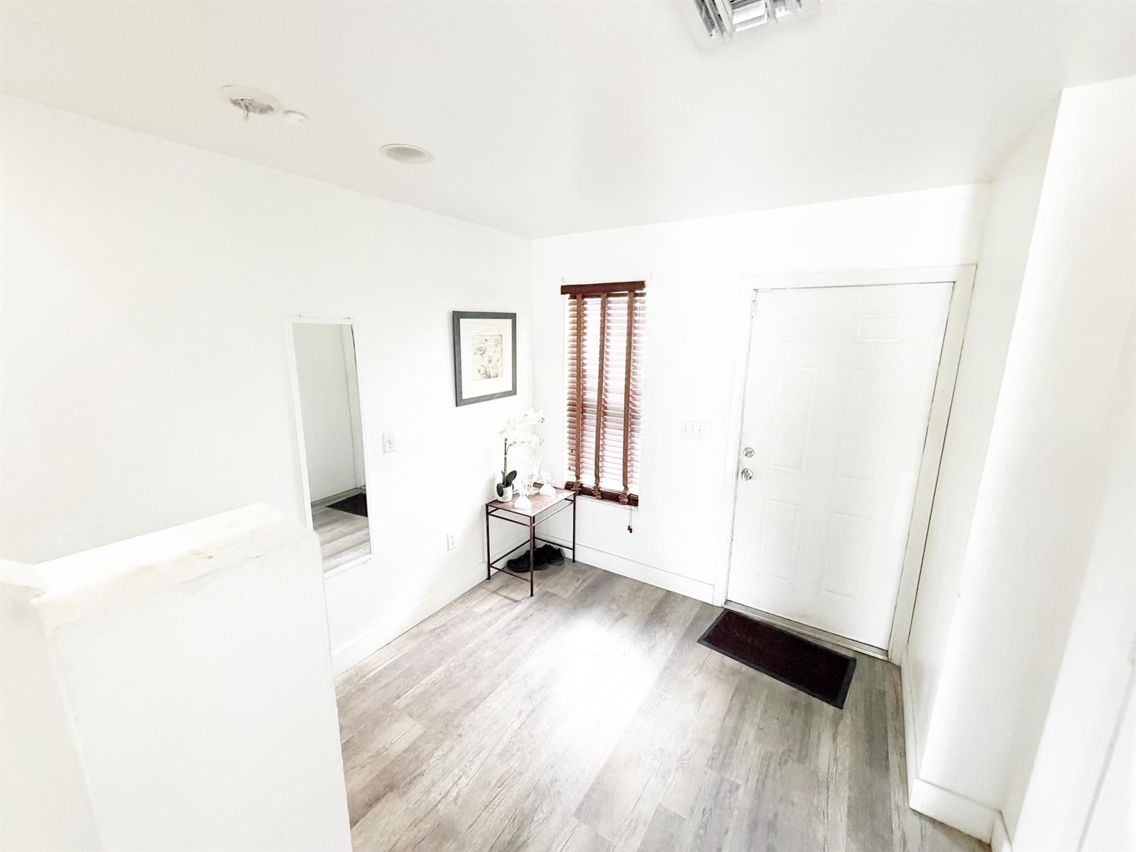 An entryway features white walls, wood-look flooring, a small side table, and a white door — 2769 NW 13th Street # 6, Pompano Beach FL 33069, POMPANO BEACH, FL