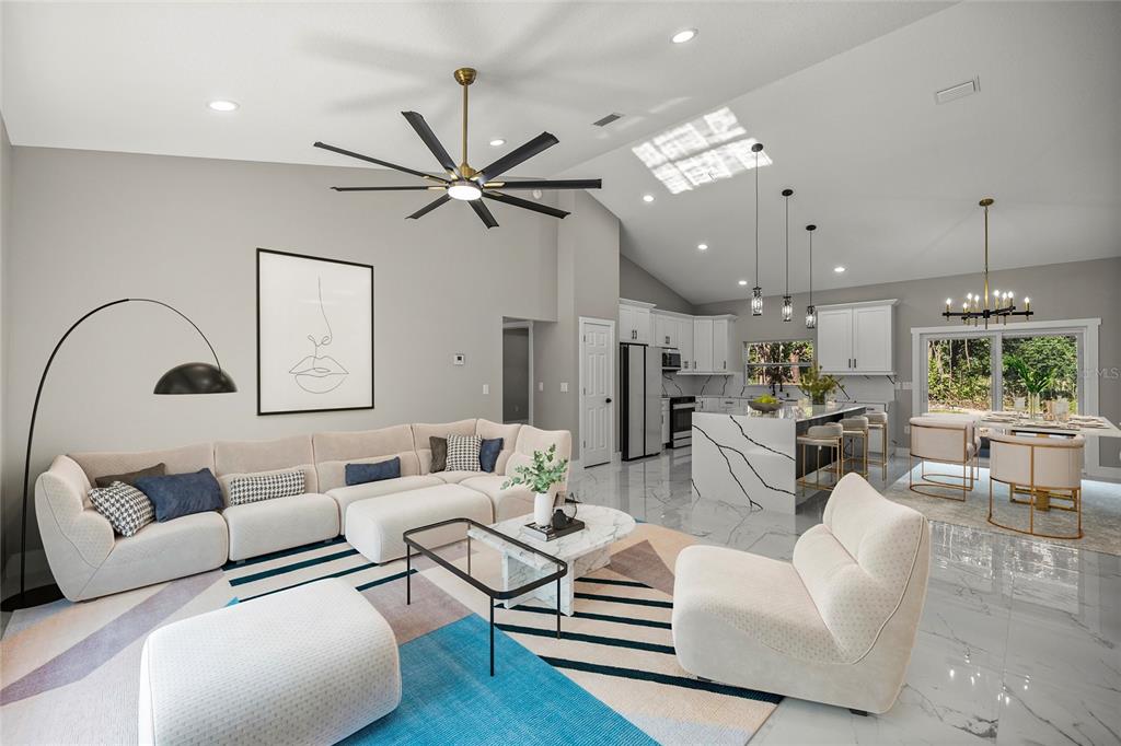 An open-concept living room and kitchen feature white marble floors, a sectional sofa, and island — 3981 SE 142ND LANE, SUMMERFIELD, FL