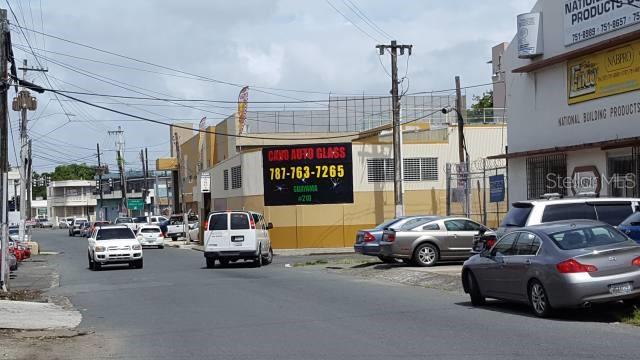 A street view showing a commercial building with an auto glass sign and parked cars — 204 GUAYAMA, SAN JUAN, PR