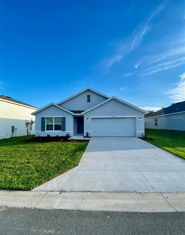 A single-story house with a light blue exterior, a two-car garage, and a concrete driveway — 10278 SE 161ST STREET, SUMMERFIELD, FL