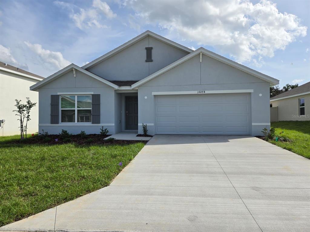 A single-story house with a gray exterior, a two-car garage, and a concrete driveway — 10278 SE 161ST STREET, SUMMERFIELD, FL