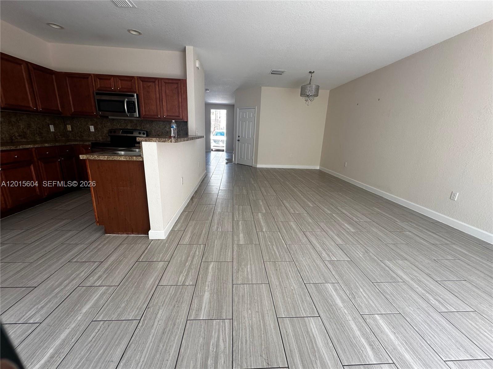 A kitchen with dark wood cabinets and a breakfast bar opens into a dining area — 1036 NE 208th St # 1036, Miami FL 33179, MIAMI, FL