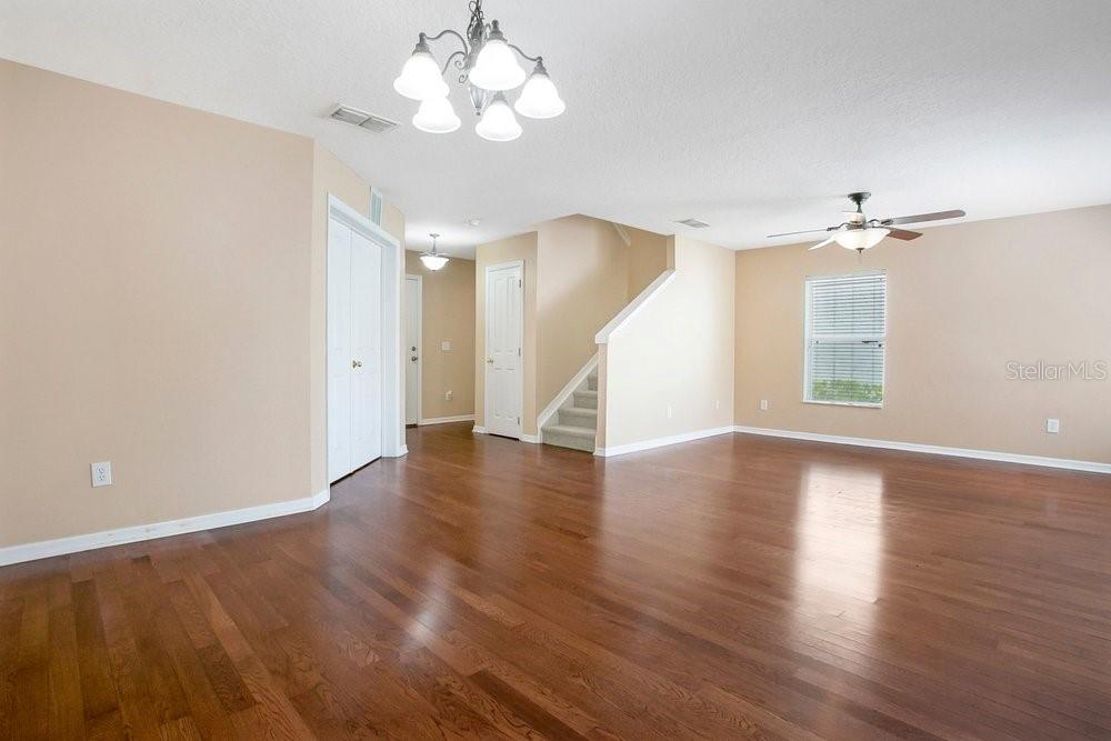 An empty living room features hardwood floors, a ceiling fan, and a staircase — 2205 GLOSSY PRIVET DRIVE, ORLANDO, FL