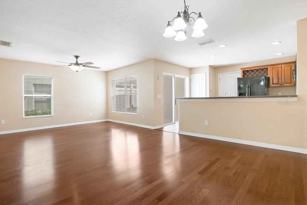 An open-concept living and dining area features hardwood floors, a ceiling fan, and kitchen pass-through — 2205 GLOSSY PRIVET DRIVE, ORLANDO, FL