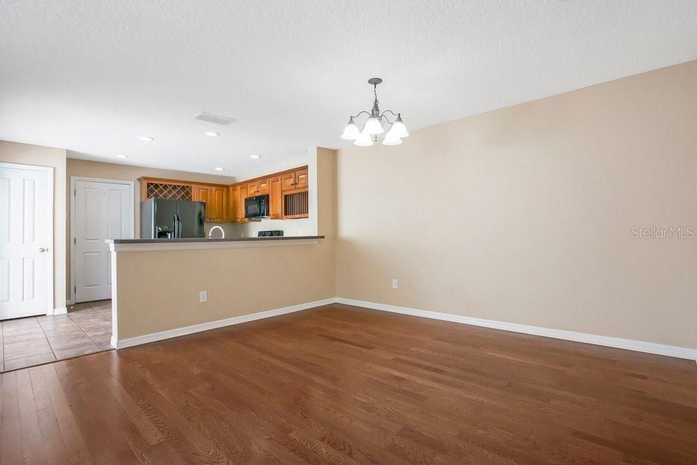 A dining area with hardwood floors opens to a kitchen with wood cabinets and appliances — 2205 GLOSSY PRIVET DRIVE, ORLANDO, FL
