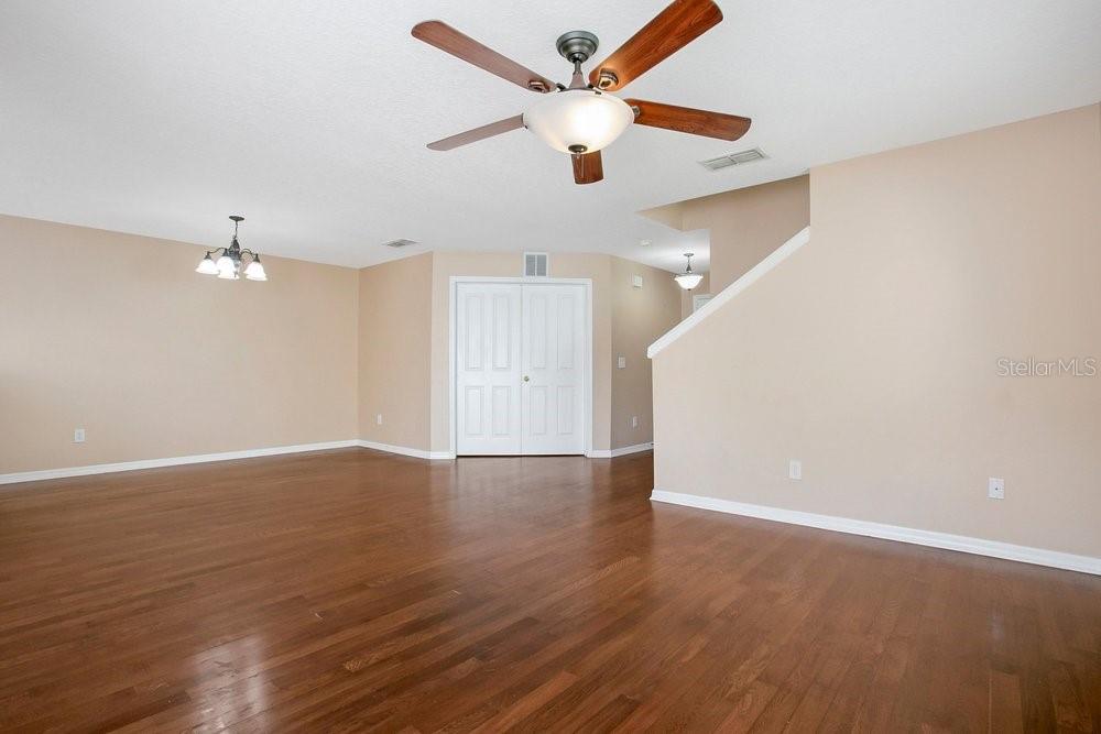 An empty living room features hardwood floors, beige walls, and a ceiling fan — 2205 GLOSSY PRIVET DRIVE, ORLANDO, FL