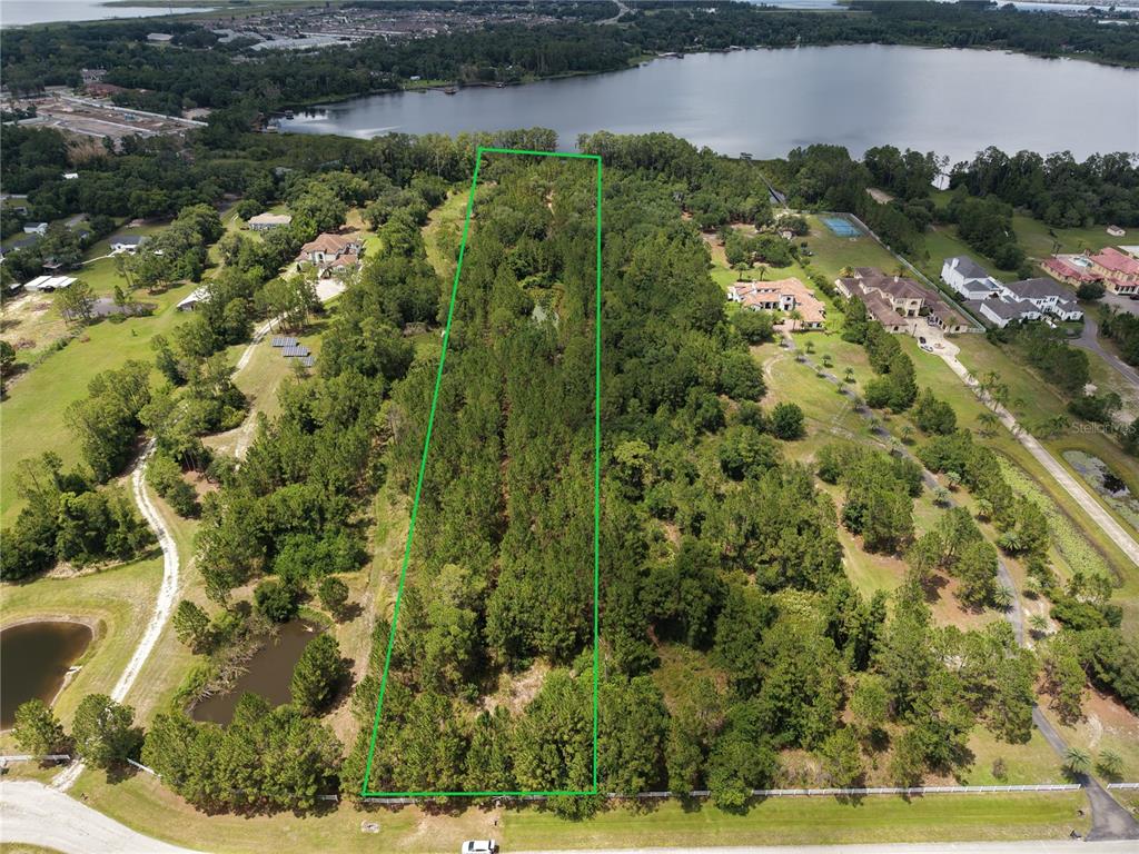 An aerial view shows a rectangular wooded lot outlined in green near a lake — 0 CARSON STREET, ST CLOUD, FL