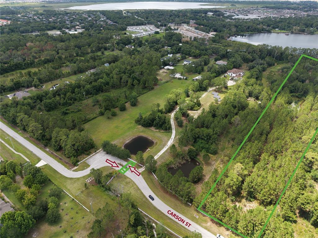 An aerial view shows a large, wooded lot outlined in green next to a residential road — 0 CARSON STREET, ST CLOUD, FL