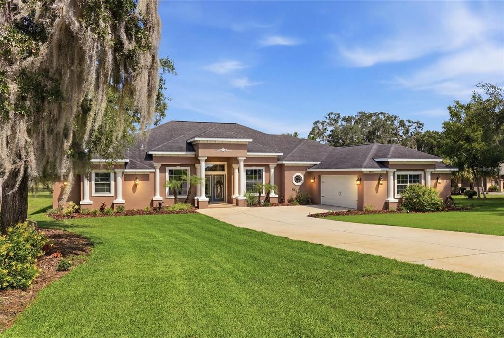A single-story tan stucco house with a dark roof, columns, and a concrete driveway — 3028 S DAVIS LAKE DRIVE, INVERNESS, FL