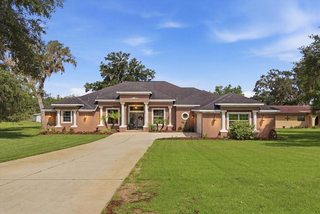 A single-story stucco house with a concrete driveway and a covered front porch entrance — 3028 S DAVIS LAKE DRIVE, INVERNESS, FL