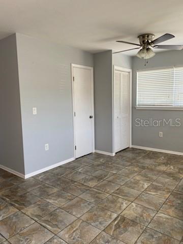 A room with light gray walls, tile flooring, a ceiling fan, and two closed doors — 512 BARCELONA AVENUE UNIT 4, VENICE, FL
