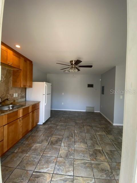 A kitchen with wood cabinets, tile flooring, and a white refrigerator leads into a living area — 512 BARCELONA AVENUE UNIT 4, VENICE, FL