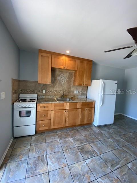 A kitchen features light wood cabinets, granite countertops, a white stove, and tiled flooring — 512 BARCELONA AVENUE UNIT 4, VENICE, FL